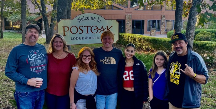 a group of people standing in front of a welcome sign at post oak lodge