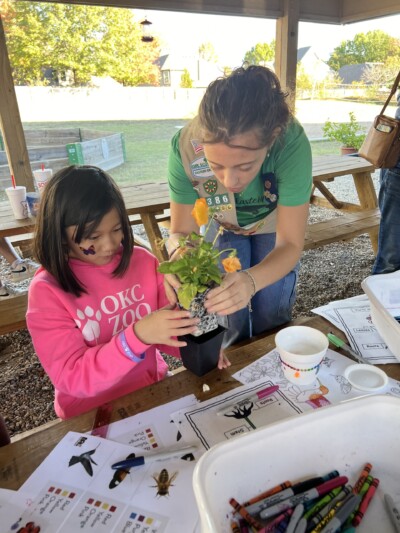 Ruby Anton helping a younger girl plant a flower