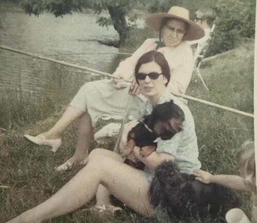 two women sitting by a creek with dogs